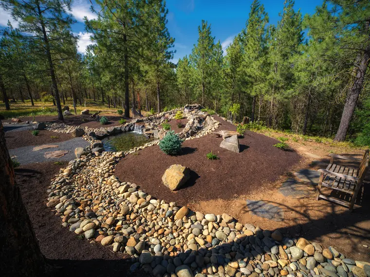 Winding river-rock dry creek bed through a planted yard